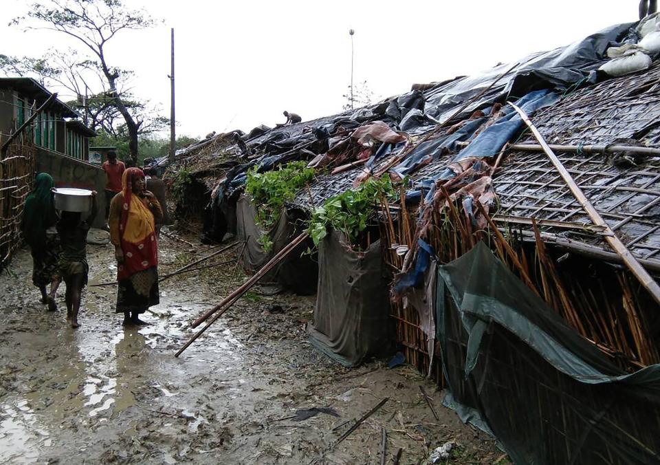 Rohingya refugees walk next to huts in a makeshift camp in Bangladesh's Cox's Bazar district on May 30, after Cyclone Mora made landfall in the region.&nbsp;The district is home to 300,000 Rohingya refugees, most of whom live in flimsy makeshift camps after fleeing persecution in neighbouring Myanmar.&nbsp;&nbsp;