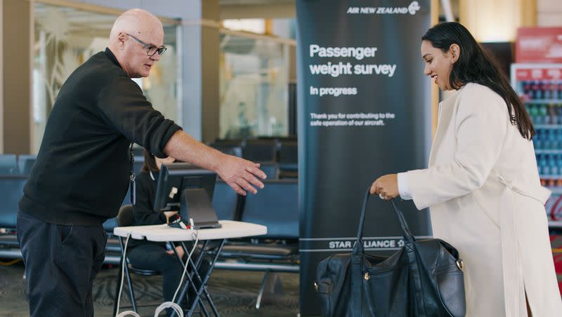 In this photo provided by Air New Zealand, a woman hands her bag to a staff member to be weighed ahead of a flight in Auckland, New Zealand, on May 29, 2023. New Zealand’s national airline is asking people to step on the scales before they board international flights.