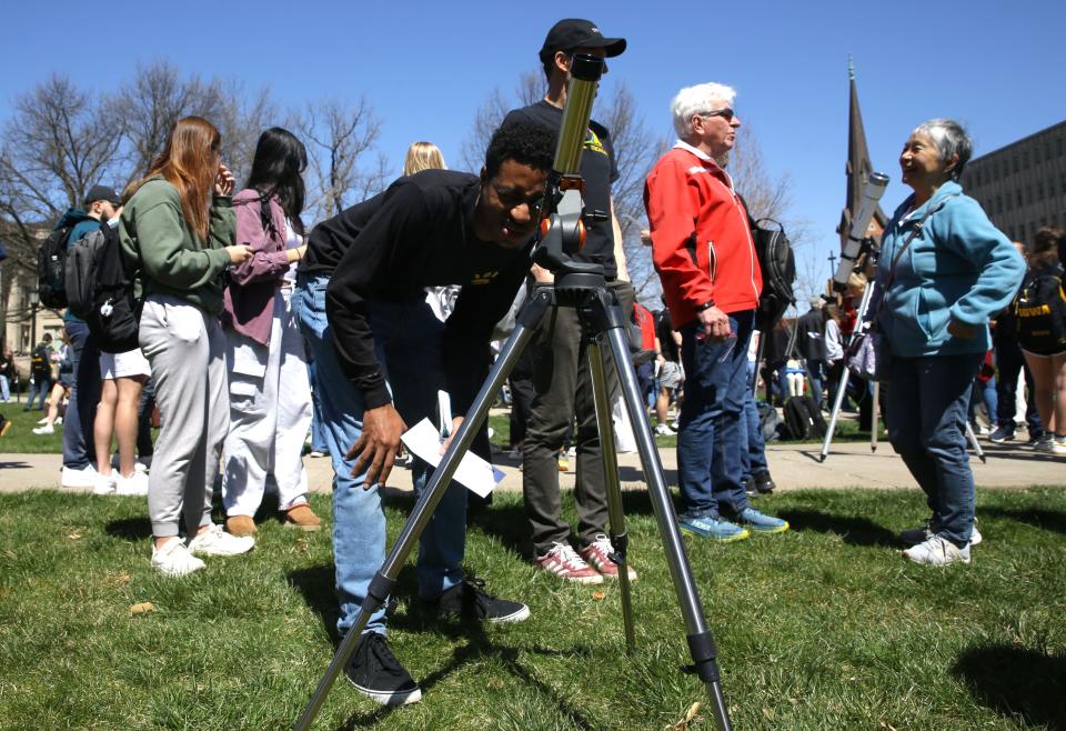 Daniel Meggo, a biomedical engineering Phd student, looks through a telescope ahead of the partial solar eclipse Monday, April 8, 2024 at the Pentacrest in downtown Iowa City, Iowa.