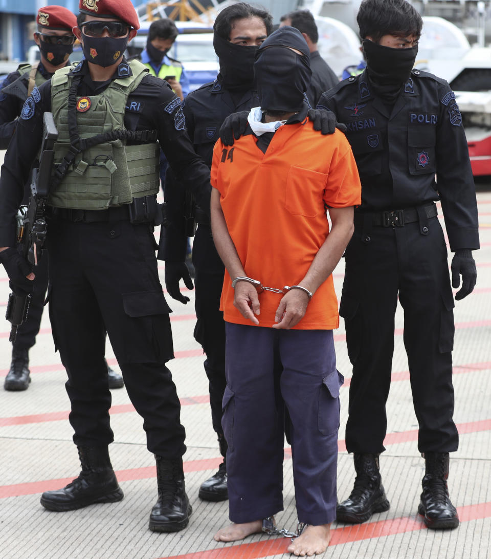 Police officers escort suspected militant Upik Lawanga, center, upon arrival at Soekarno-Hatta International Airport in Tangerang, Indonesia, Wednesday, Dec. 16, 2020. Indonesian authorities on Wednesday transferred suspected militants arrested in recent weeks to the country’s capital. Among them are Aris Sumarsono, known as Zulkarnaen, and Lawanga, the ringleaders of the al-Qaida-linked Jemaah Islamiyah network who have eluded capture for more than a decade. (AP Photo/Achmad Ibrahim)