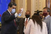 FILE - In this Dec. 8, 2020 file photo, Venezuela's President Nicolas Maduro playfully sprays a journalist with disinfectant as he exits a press conference at Miraflores Presidential Palace in Caracas, Venezuela, amid the new coronavirus pandemic. Attorneys for the cash-strapped government blame the impact of U.S. sanctions for its inability to make an initial $18 million down payment to the United Nations for doses of the U.N.-supplied vaccines, whose deadline has already passed. (AP Photo/Matias Delacroix, File)