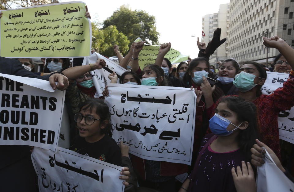 Members of Pakistan Hindu Council hold a protest against the attack on a Hindu temple in the northwestern town of Karak, in Karachi, Pakistan, Thursday, Dec. 31, 2020. Pakistani police arrested 14 people in overnight raids after a Hindu temple was set on fire and demolished by a mob led by supporters of a radical Islamist party, officials said. The temple's destruction Wednesday in the northwestern town of Karak drew condemnation from human rights activists and the minority Hindu community. The placard, center, reads as "File blasphemy cases on the attackers for desecration of minority's worship places." (AP Photo/Fareed Khan)