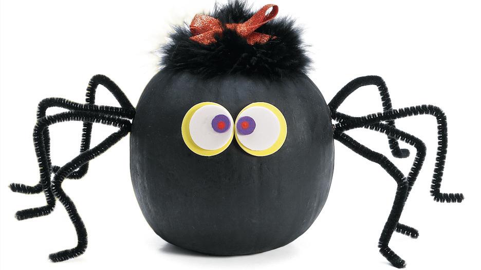 Pumpkin decorated to look like a spider with paper eyes and pipe cleaner legs