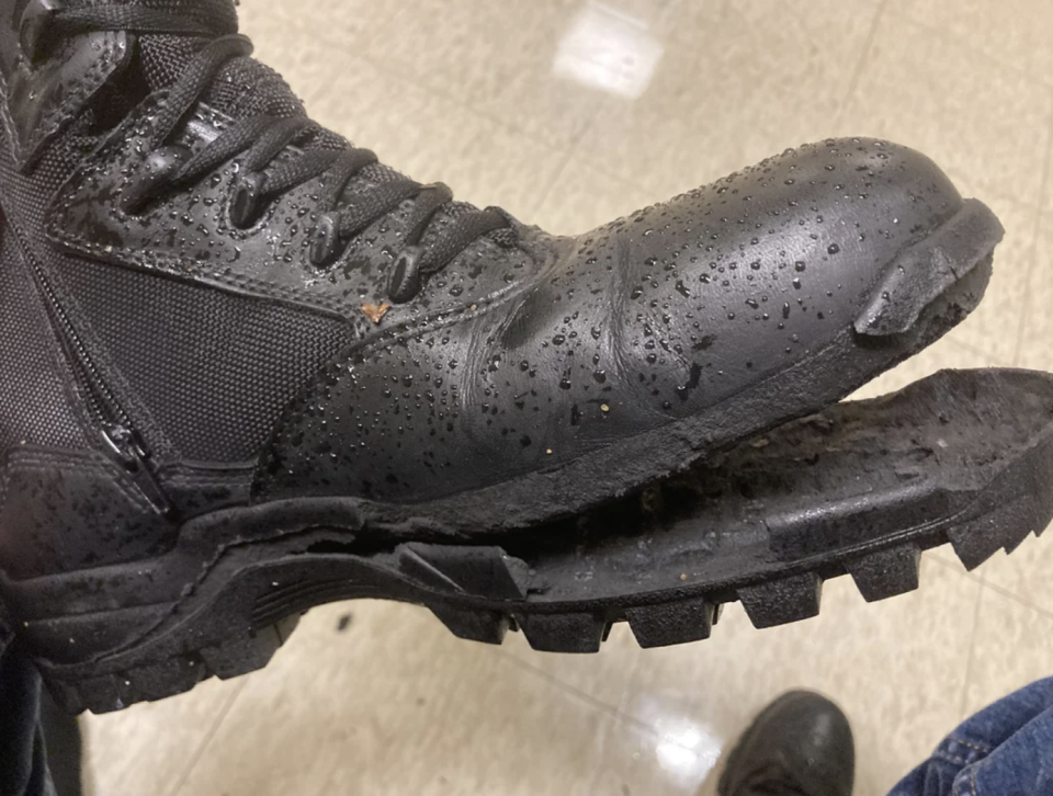 Close-up of a worn-out black boot with noticeable treads, covered in small droplets