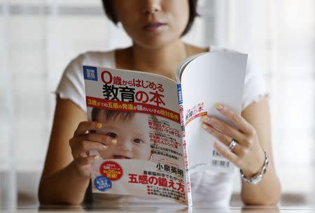 Sayaka Osakabe, founder of "Matahara net," a support group calling for legislation outlining more support for working women, reads an educational magazine for expectant mothers in their first trimester, in her house in Kawasaki, south of Tokyo September 11, 2014. REUTERS/Yuya Shino