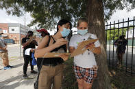 Edif Madrid, right, and Rosa Guillen wait in a line for COVID-19 testing at a mobile testing site in New Orleans, Wednesday, July 8, 2020. Testing sites in New Orleans have been running out of their daily allocation of tests within minutes of opening. (AP Photo/Gerald Herbert)