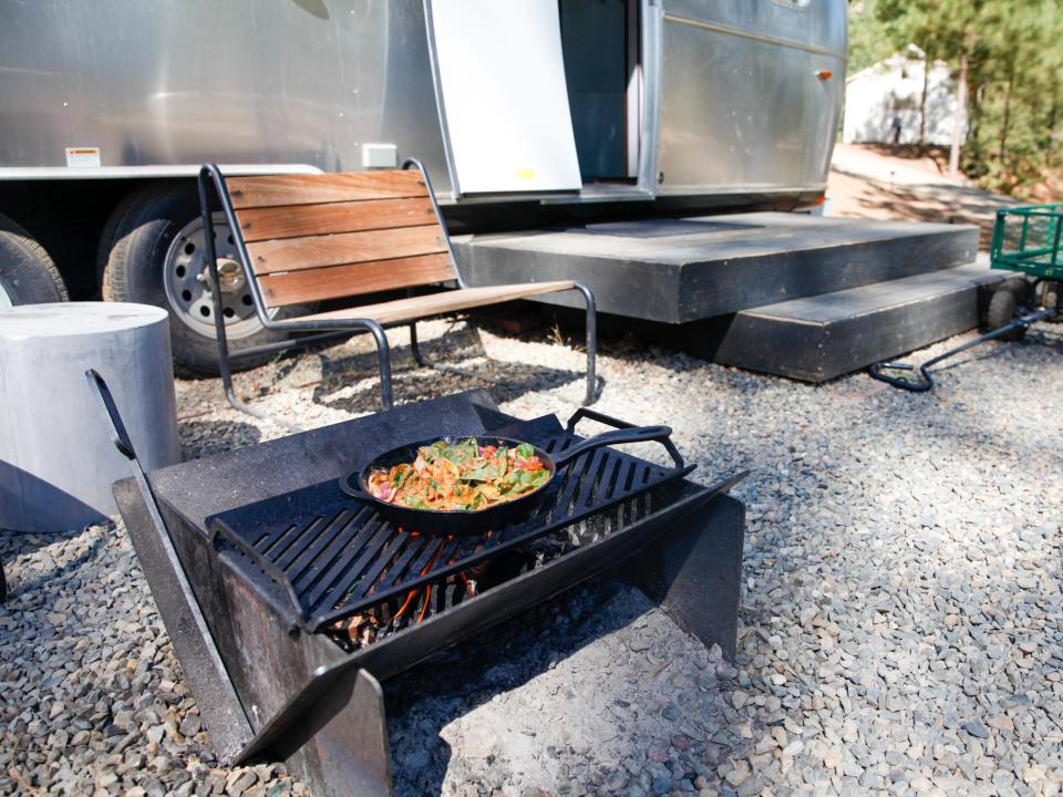 a pan of food cooking over a fire next to outdoor seats