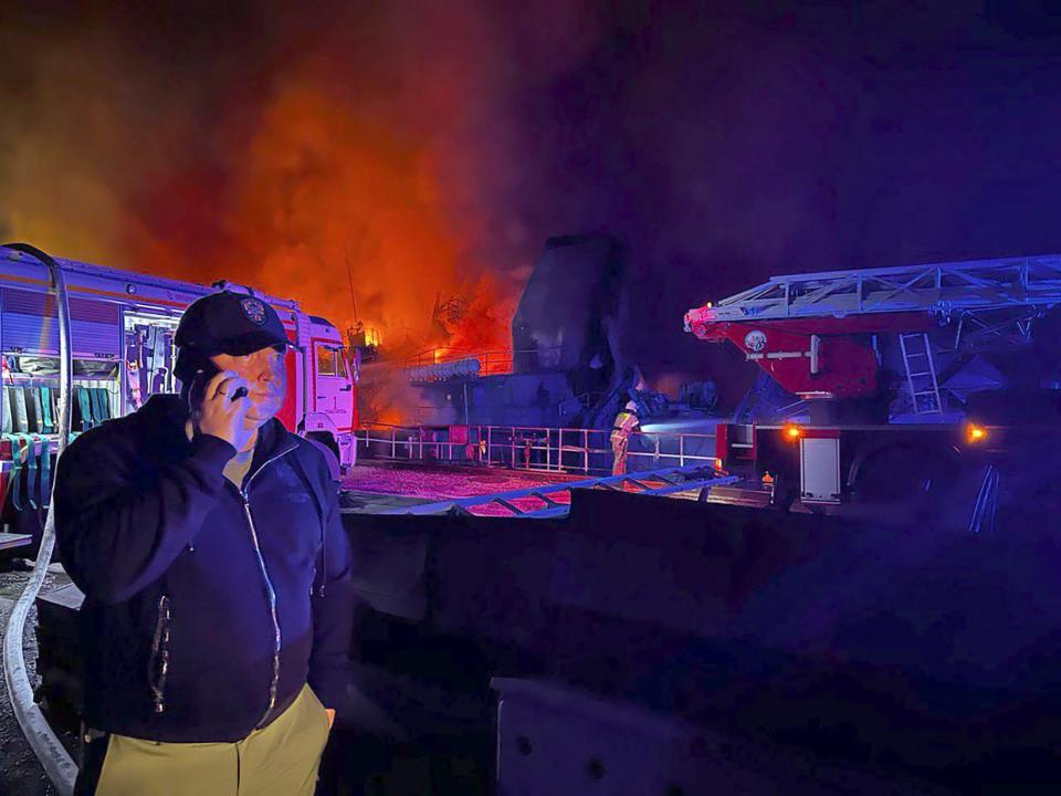 n this handout photo released by the Governor of Sevastopol Mikhail Razvozhaev telegram channel on Wednesday, Sept. 13, 2023, Razvozhaev speaks on the mobile phone as smoke and flame rise from a burning Sevastopol Shipyard in Crimea.