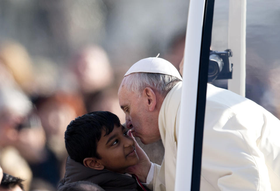 Pope Francis kisses a child as he arrives for his weekly general audience in St. Peter's Square at the Vatican, Wednesday, Jan. 8, 2014. (AP Photo/Alessandra Tarantino)