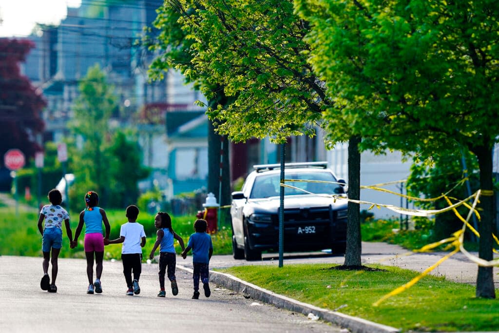 Children walk hand in hand out near the scene of a shooting at a supermarket in Buffalo, N.Y., Sunday, May 15, 2022. (AP Photo/Matt Rourke)