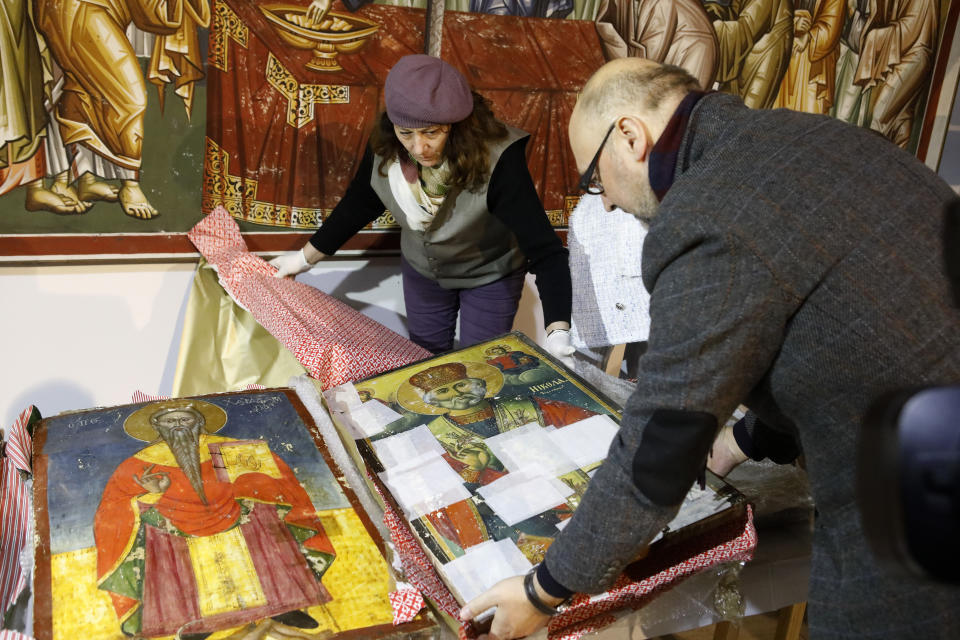 Sasho Cvetkovski, right, member of the Academy of Sciences of North Macedonia and a museum worker unpack an icon returned from Albania at the National museum in Skopje, North Macedonia, late Friday, Dec. 15, 2023. Albania on Friday returned 20 icons to neighboring North Macedonia that were stolen a decade ago. (AP Photo/Boris Grdanoski)