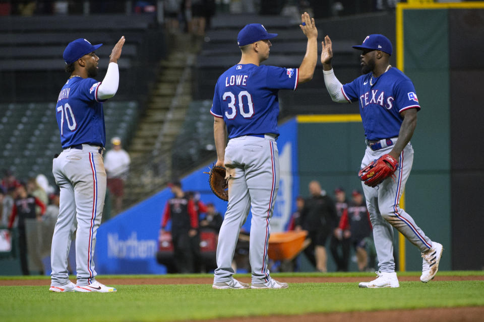 Texas Rangers' Nathaniel Lowe greets Adolis Garcia, right, as Ezequiel Duran (70) waits after the Rangers defeated the Cleveland Guardians in the second game of a baseball doubleheader in Cleveland, Tuesday, June 7, 2022. (AP Photo/Phil Long)