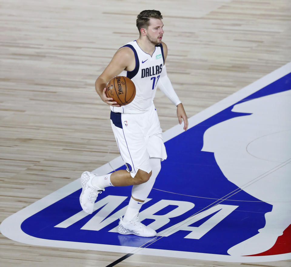 Dallas Mavericks guard Luka Doncic (77) dribbles over the NBA logo during the first half of an NBA basketball game Tuesday, Aug. 11, 2020, in Lake Buena Vista, Fla. (Kim Klement/Pool Photo via AP)