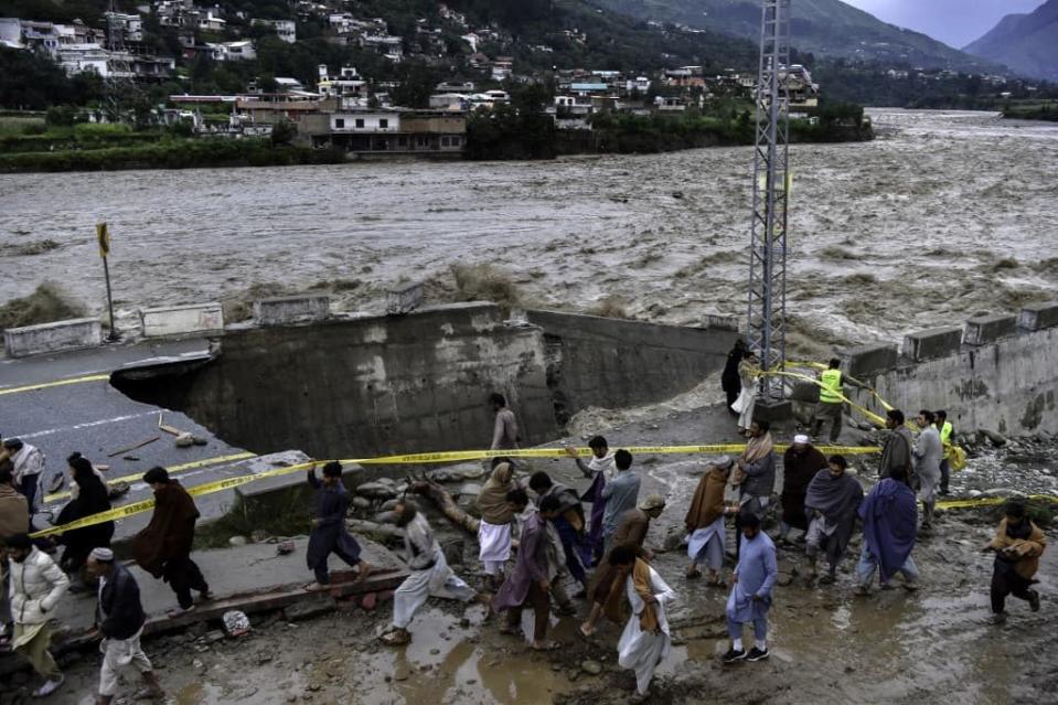 Des personnes près d'une route détruite par les pluies dans la vallée du Swat, le 27 août 2022. - ABDUL MAJEED / AFP