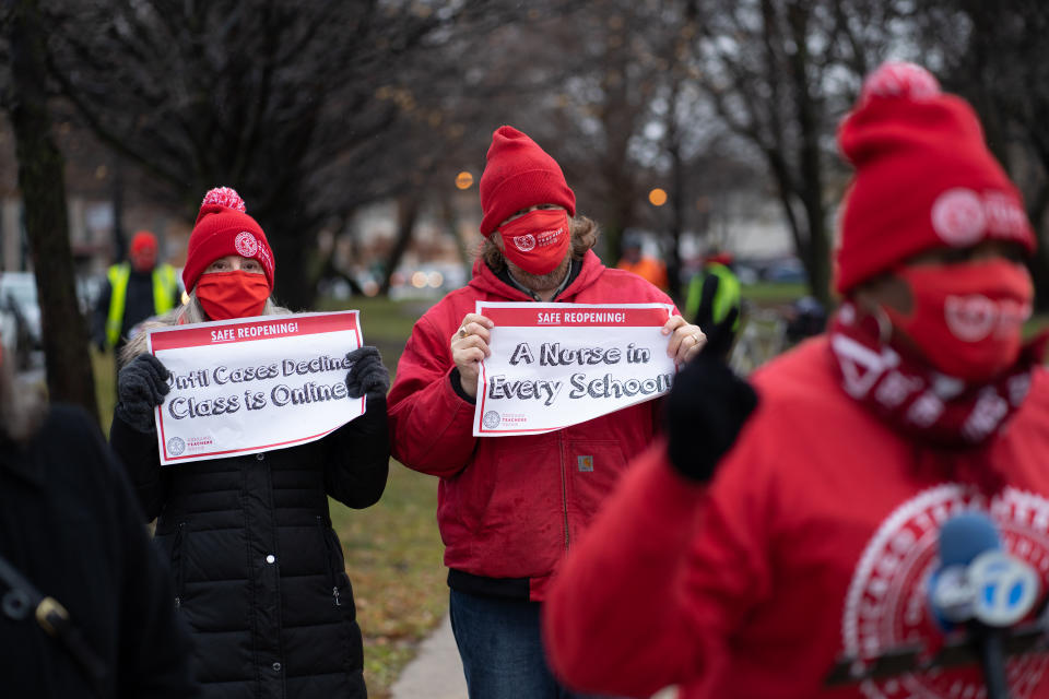 Chicago Teachers Union members display signs while former teacher Tara Stamps speaks ahead of a car caravan where teachers and supporters gathered to demand a safe and equitable return to in-person learning during the COVID-19 pandemic in Chicago, IL on December 12, 2020. (Max Herman/NurPhoto via Getty Images)