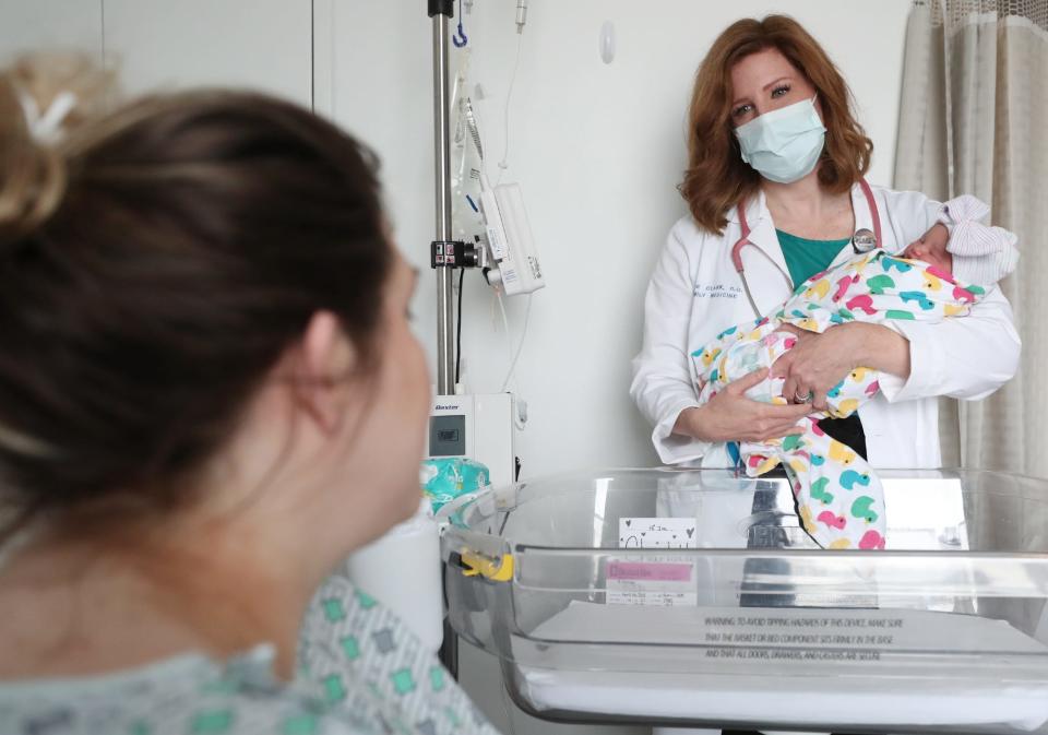 Dr. Katie Clark holds newborn Charlotte Long as she talks with Brittany, the baby's mom, on the Mother Baby Unit at Cleveland Clinic Akron General.