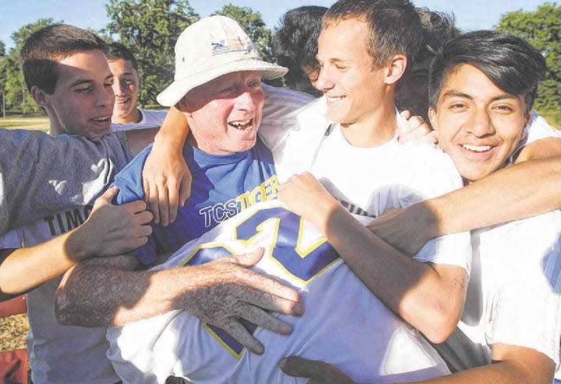 Coach William Bills is embraced by his players on Wednesday, Sept. 18, 2013, after notching his 1,000th career coaching victory at Timothy Christian.