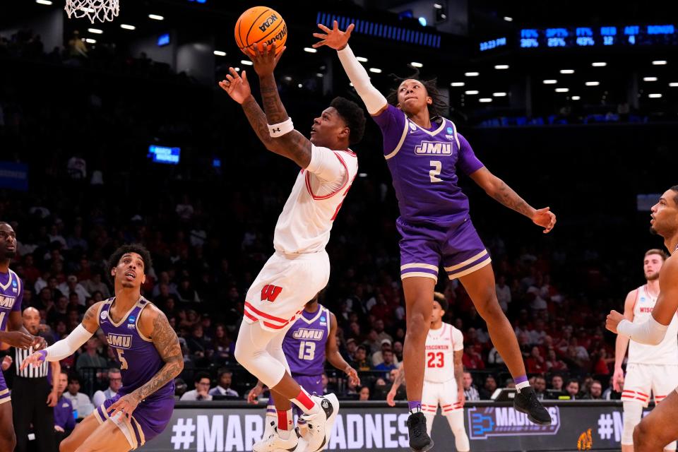 Then with Wisconsin, guard AJ Storr shoots the ball past James Madison forward Raekwon Horton during a NCAA tournament game at the Barclays Center in Brooklyn, New York, on March 22, 2024.