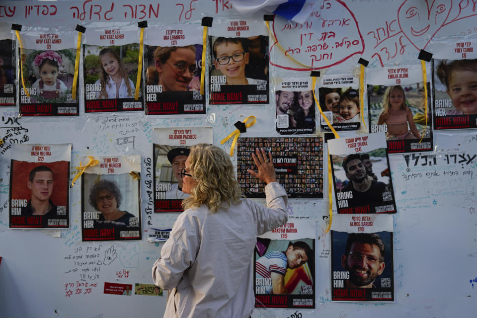 A woman looks at photographs of hostages, mostly Israeli civilians who were abducted during the Oct. 7 Hamas attack on Israel Israel, in Tel Aviv, Israel, on Friday, Nov. 24, 2023. Friday marks the start of a four-day cease-fire in the Israel-Hamas war, during which the Gaza militants pledged to release 50 hostages in exchange for 150 Palestinians imprisoned by Israel. (AP Photo/Ariel Schalit)