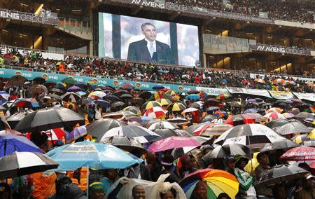 REFILE - CORRECTING GRAMMAR South Africans brave the rain as they listen to U.S. President Barack Obama speak during a memorial service for Nelson Mandela at FNB Stadium in Johannesburg, South Africa December 10, 2013. World leaders from Obama to Cuba's Raul Castro joined thousands of South Africans to honour Mandela on Tuesday in a memorial celebrating his gift for uniting enemies across political and racial divides. REUTERS/Kevin Lamarque