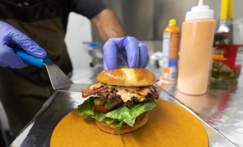 Juan Fernandez plates a freshly grilled burger on Thursday, June 16, 2022. Sweet Sugar High won Star-Telegram Readers’ Choice Best Burger contest in the food truck category.