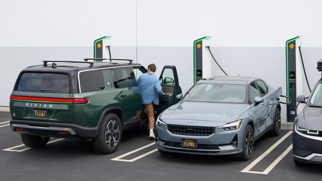 a person climbing into rivian r1s passenger side while it charges