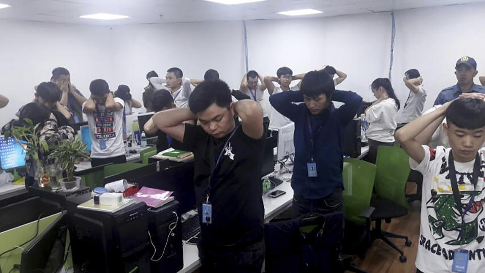 In this Oct. 9, 2019, photo provided by Philippine Bureau of Immigration, foreign nationals, mostly Chinese put their hands on their heads during a raid of their company premises in Manila, Philippines. Philippine police and immigration authorities said they have arrested more than 500 illegally working foreigners, mostly Chinese involved in telecommunications and investment scams, in one of the biggest such mass arrests this year. (Philippine Bureau of Immigration Via AP)