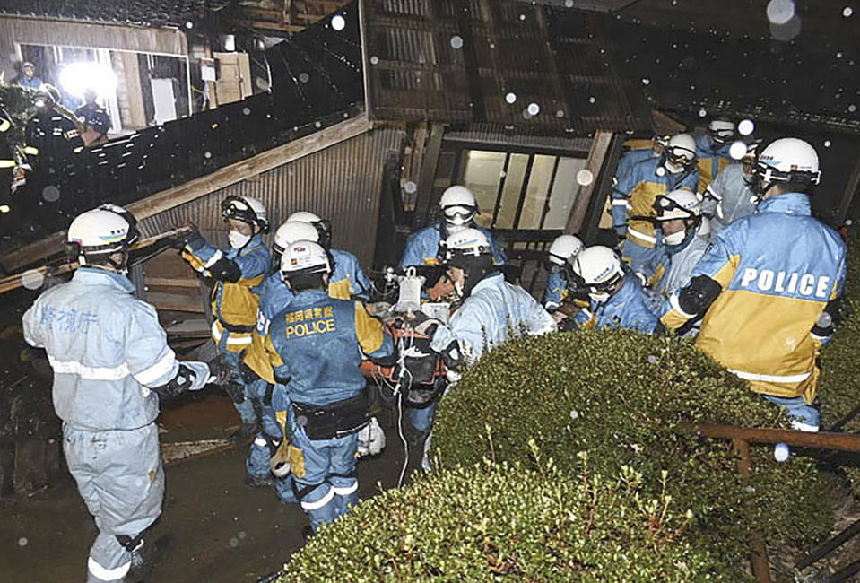 In this photo released by Metropolitan Police Department via Kyodo News, police officers rescue a woman from a collapsed house in Suzu, Ishikawa prefecture, Japan, Saturday, Jan. 6, 2024. The woman in her 90s was pulled alive from the collapsed house late Saturday, 124 hours after a major quake slammed the region, killing scores of people, toppling buildings and setting off landslides. (Metropolitan Police Department/Kyodo News via AP)