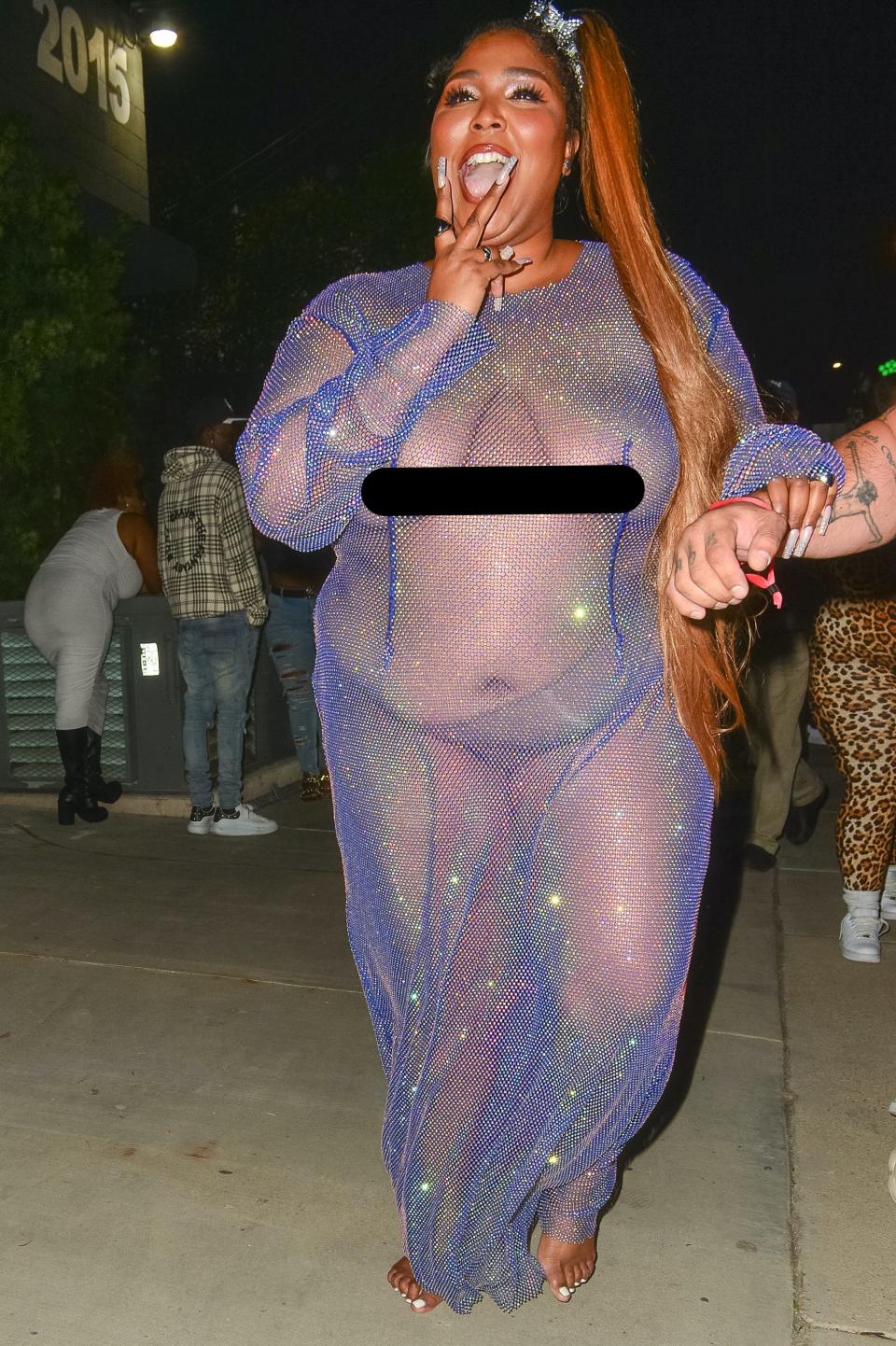 Lizzo walks in a see-through dress with no shoes.