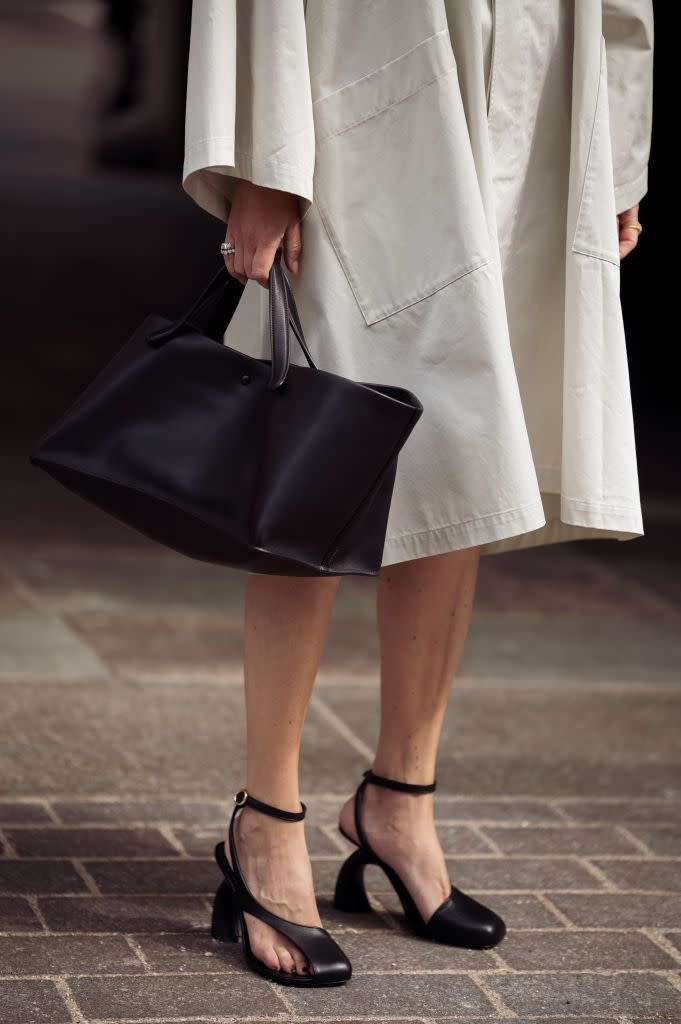 a woman wearing a pair of black asymmetrical square toe heels with toe cutouts with trench coat and black leather bag on the street in copenhagen in a roundup of the best heels for wide feet 2024