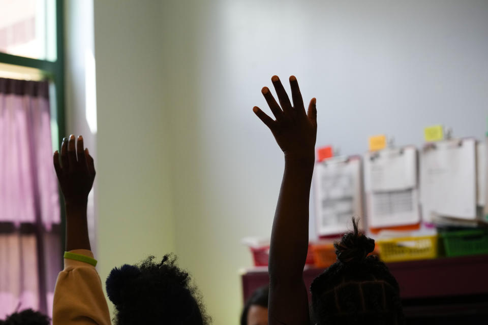 Third graders raise their hands during class at Schaumburg Elementary, part of the ReNEW charter network, in New Orleans, Wednesday, April 19, 2023. (AP Photo/Gerald Herbert)