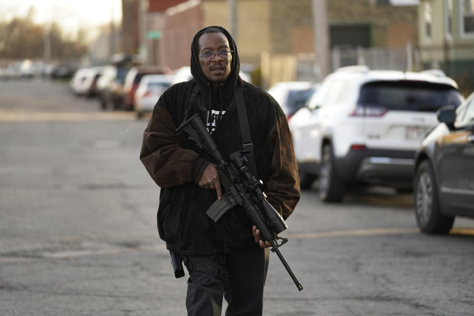 Erick Jordan walks down a street with his rifle offering protection near a news conference Friday, Nov. 19, 2021 in Kenosha, Wis. Kyle Rittenhouse was acquitted of all charges after pleading self-defense in the deadly Kenosha shootings that became a flashpoint in the nation's debate over guns, vigilantism and racial injustice. (AP Photo/Paul Sancya)