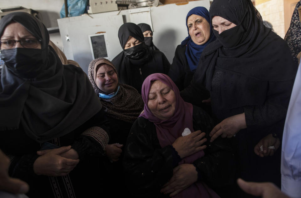 Palestinian relatives mourn over the bodies of four brothers from the Tanani family who were found under the rubble of a destroyed house following Israeli airstrikes in Beit Lahiya, northern Gaza Strip, Friday, May 14, 2021. (AP Photo/Khalil Hamra)