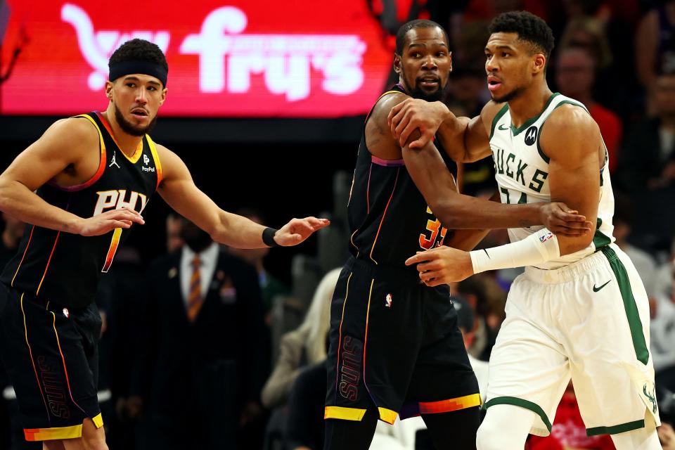 Milwaukee Bucks forward Giannis Antetokounmpo (34) is defended by Phoenix Suns forward Kevin Durant (35) and guard Devin Booker (1) during the third quarter at Footprint Center in Phoenix on Feb. 6, 2024.