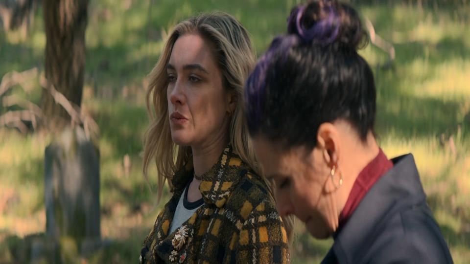 Two women standing in a graveyard.