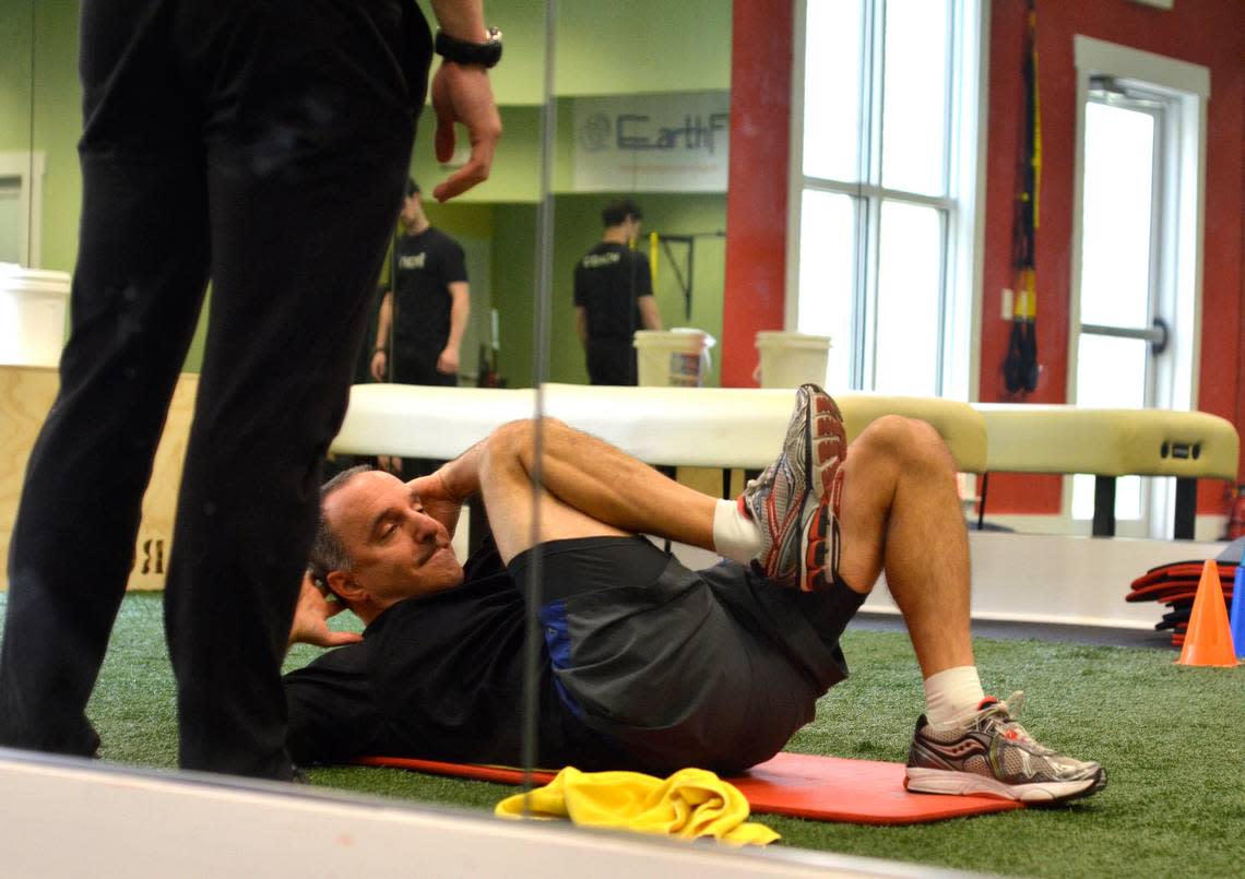 Personal trainer and EarthFIT owner Ian Hart, left, supervises and encourages client Sam Levin, right, March 1 at the Lady’s Island gym during an exercise from Hart’s Back Pain Relief4Life program. Staff photo