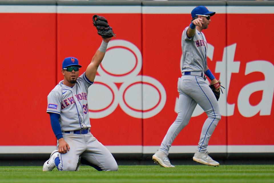 New York Mets center fielder Rafael Ortega, left, reacts after making a catch on a ball hit by Baltimore Orioles' Ramon Urias during the fourth inning of a baseball game, Sunday, Aug. 6, 2023, in Baltimore. Mets' left fielder Jeff McNeil, right, looks on.