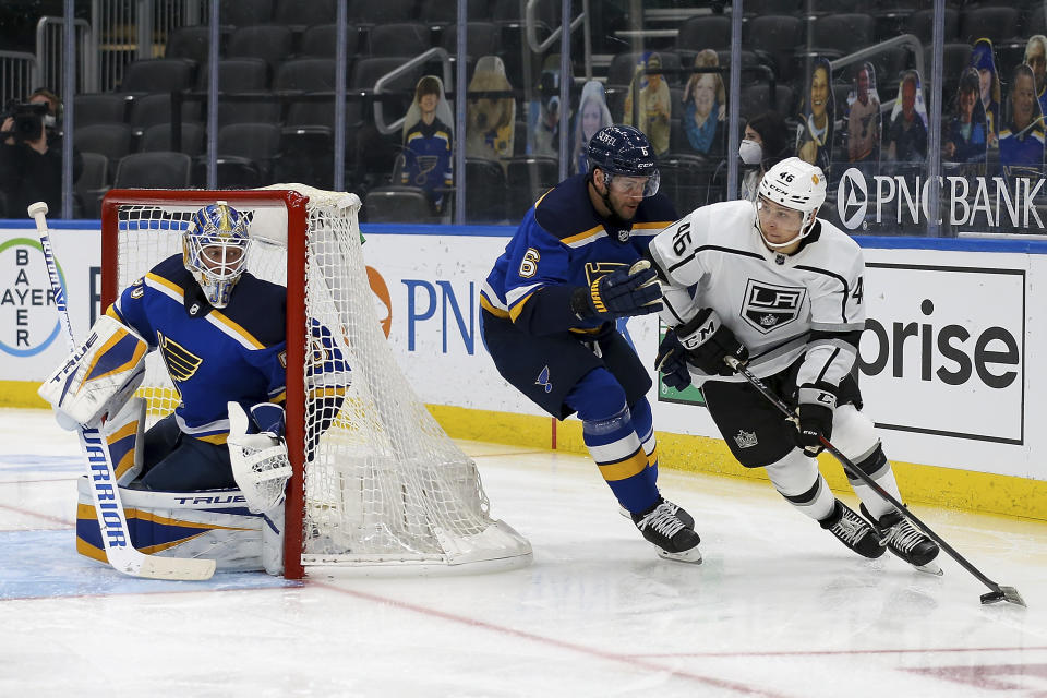 Los Angeles Kings' Blake Lizotte (46) controls the puck while under pressure from St. Louis Blues' Marco Scandella (6) while goaltender Jordan Binnington (50) watches during the third period of an NHL hockey game Wednesday, Feb. 24, 2021, in St. Louis. (AP Photo/Scott Kane)