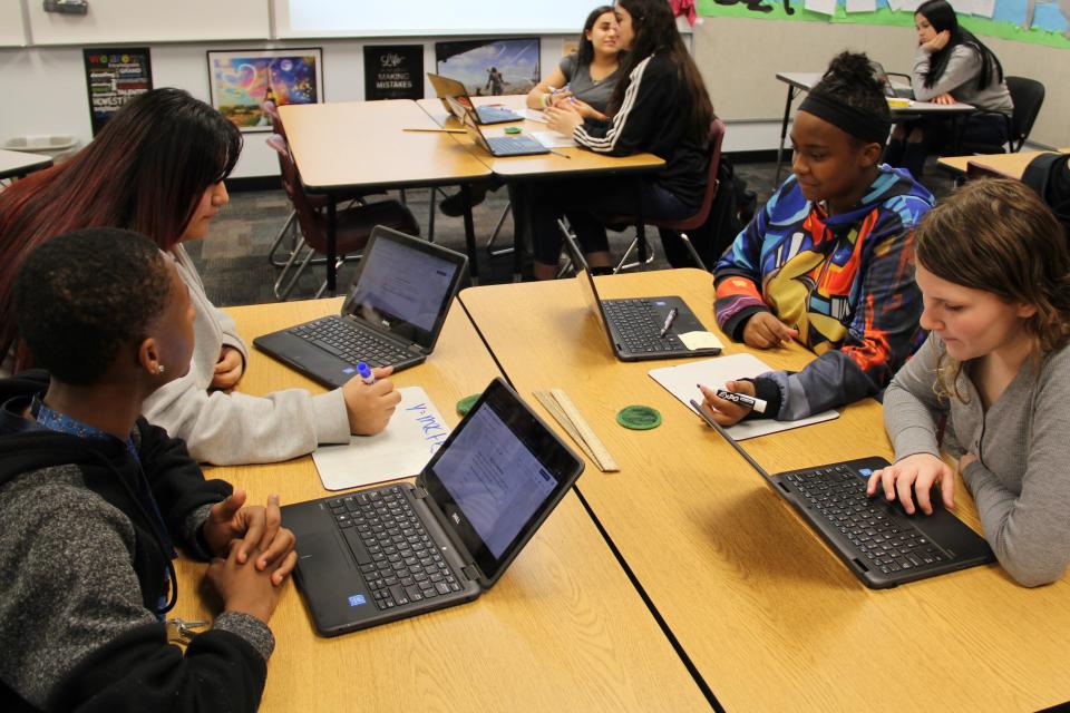 In math class, students at Rhodes Junior High in Mesa, Arizona, work on laptops but also solve word problems in groups using a white board.