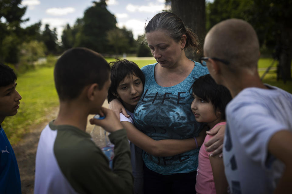 Olga Lopatkina abraza a sus hijos adoptivos en un parque de Loue (Francia) el 2 de julio del 2022. Lopatkina se separó de los chicos en medio de la guerra en Ucrania y los niños fueron llevados a Rusia. Pero luego de arduas negociaciones logró reunirse nuevamente con ellos. (AP Photo/Jeremías González)