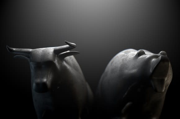 Grey bull and bear figurines with a black and grey background.