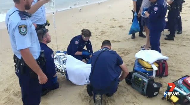 Paramedics treat the victim on the sand at Little Congwong Beach. Source: 7 News