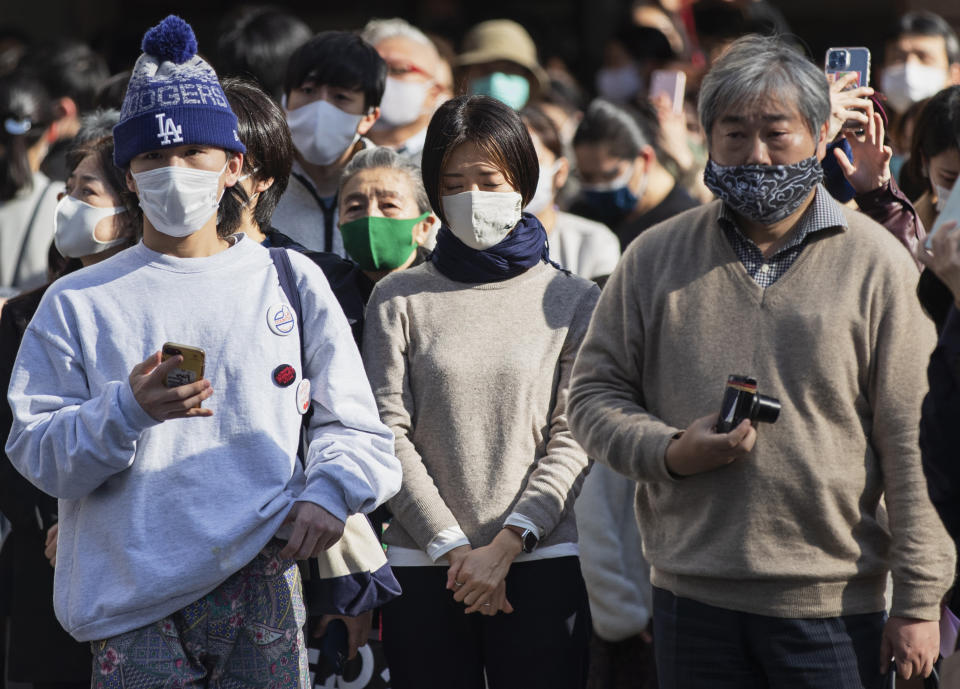 One of the bystanders waiting at a traffic intersection closes her eyes when an annual tribute started at 2:46 p.m. for the victims of a 2011 disaster in Tokyo Thursday, March 11, 2021. Japan is marking the 10th anniversary Thursday of the earthquake, tsunami and nuclear disaster that hit the northeastern region. (AP Photo/Hiro Komae)