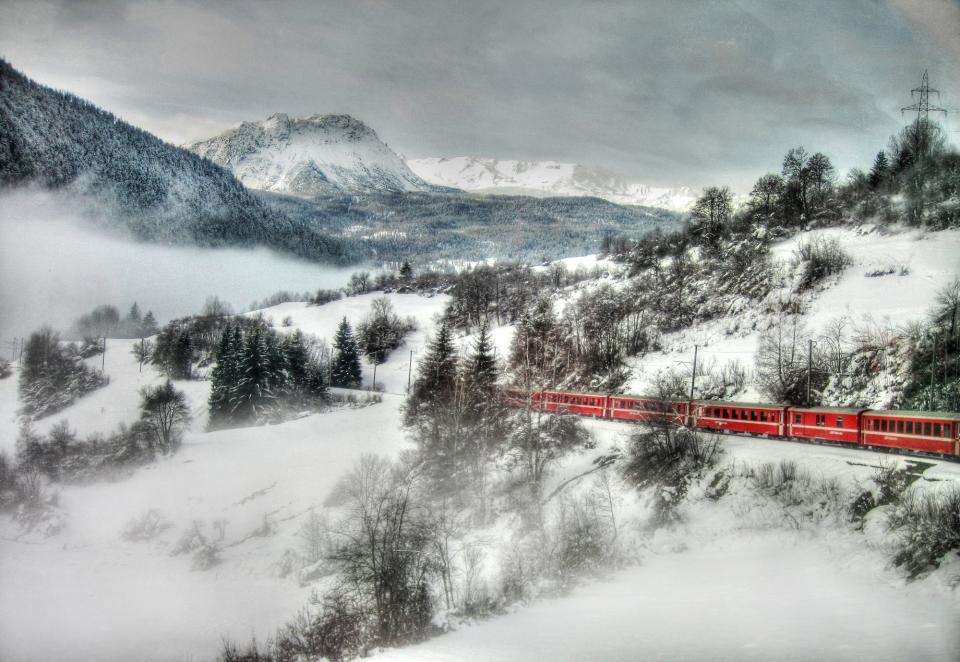 Switzerland's Glacier Express surrounded by snowy mountains and trees