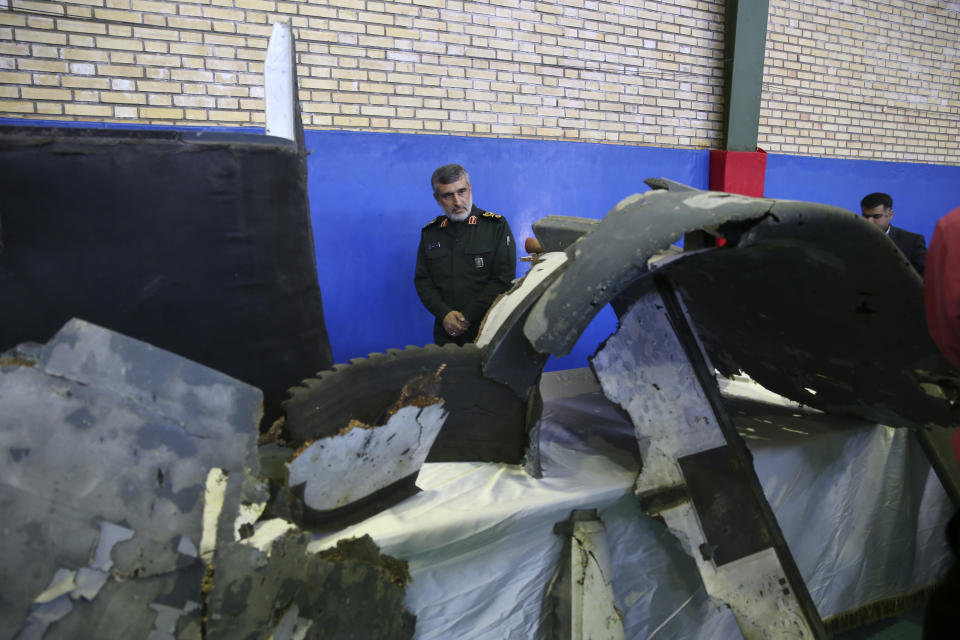 Head of the Revolutionary Guard's aerospace division Gen. Amir Ali Hajizadeh looks at debris from what the division describes as the U.S. drone which was shot down on Thursday, in Tehran, Iran, Friday, June 21, 2019. Major airlines from around the world on Friday began rerouting their flights to avoid areas around the Strait of Hormuz following Iran's shooting down of a U.S. military surveillance drone there, as America warned commercial airliners could be mistakenly attacked. Hajizadeh said on Friday, Iran had warned a U.S. military surveillance drone several times before launching a missile at it. (Meghdad Madadi/Tasnim News Agency/via AP)