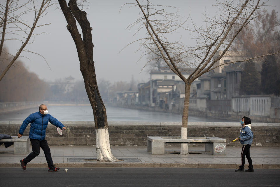 A man and girl wear face masks as they play badminton near the closed Forbidden City in Beijing, Monday, Jan. 27, 2020. China on Monday expanded sweeping efforts to contain a viral disease by postponing the end of this week's Lunar New Year holiday to keep the public at home and avoid spreading infection. (AP Photo/Mark Schiefelbein)