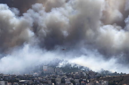A firefighting helicopter operates over a raging wildfire at the Kareas suburb, east of Athens, Greece July 17, 2015. REUTERS/Alkis Konstantinidis