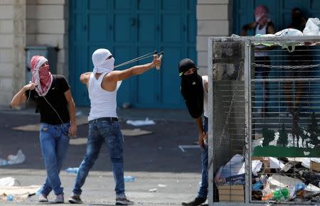 A Palestinian protester uses a slingshot to hurl stones towards Israeli troops during clashes in the West Bank city of Bethlehem July 21, 2017. REUTERS/Mussa Qawasma