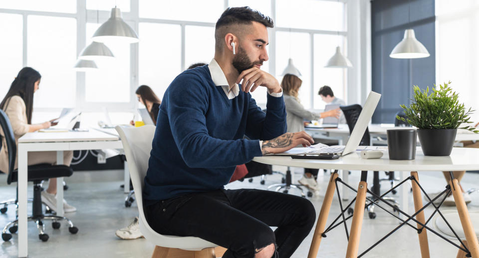 Man sits in front of his laptop wearing headphones.