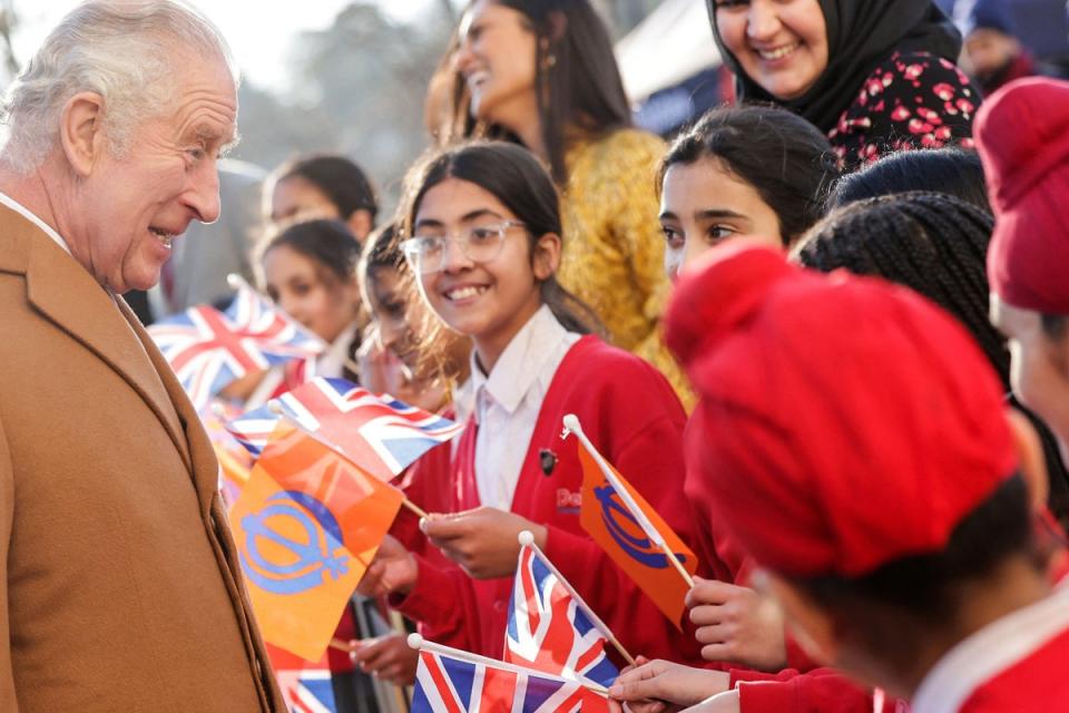 King Charles III meets school children waving flags during his visit to the newly built Guru Nanak Gurdwara in Luton on December 6  (POOL/AFP via Getty Images)